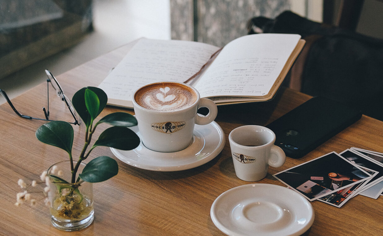 A delicious Miscela d'Oro cappuccino, on a desk with a notebook